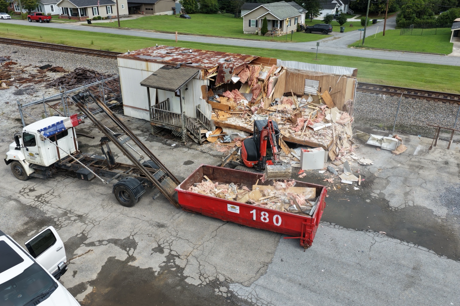 Aerial view of an outbuilding being demolished with an excavator and 180 dumpster on site